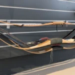 Mehrere Reiterbögen hängen gespannt an einer Wand.