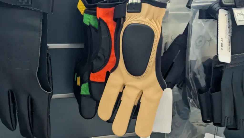 Verschiedene Schießhandschuhe aus Leder hängen an einer Wand.